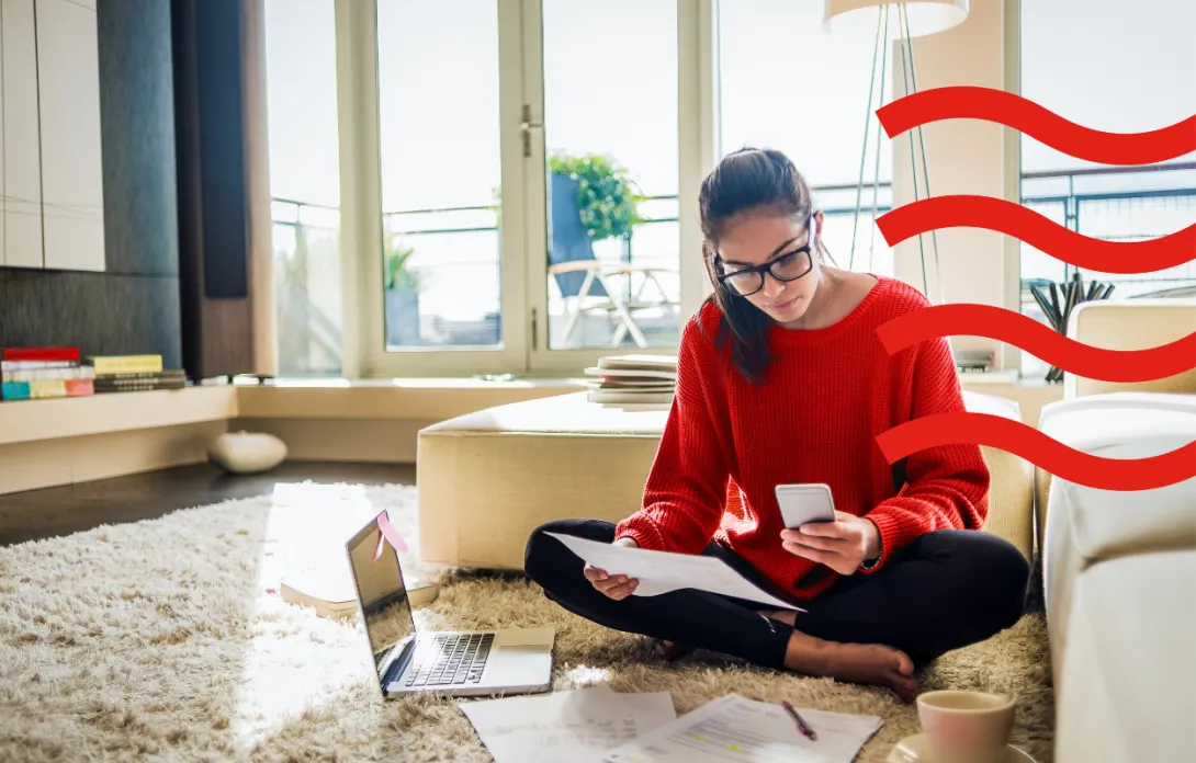 Woman checking letters and her phone while sitting on the floor