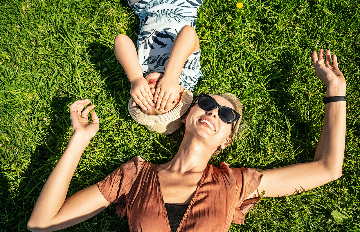 A woman and a little kid laying on the grass