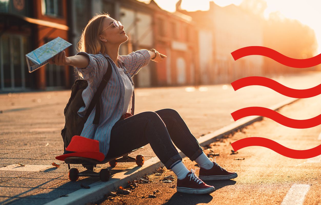 A young woman sits on a skateboard in the street