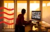 Someone working on their PC while looking out the window at the sunset