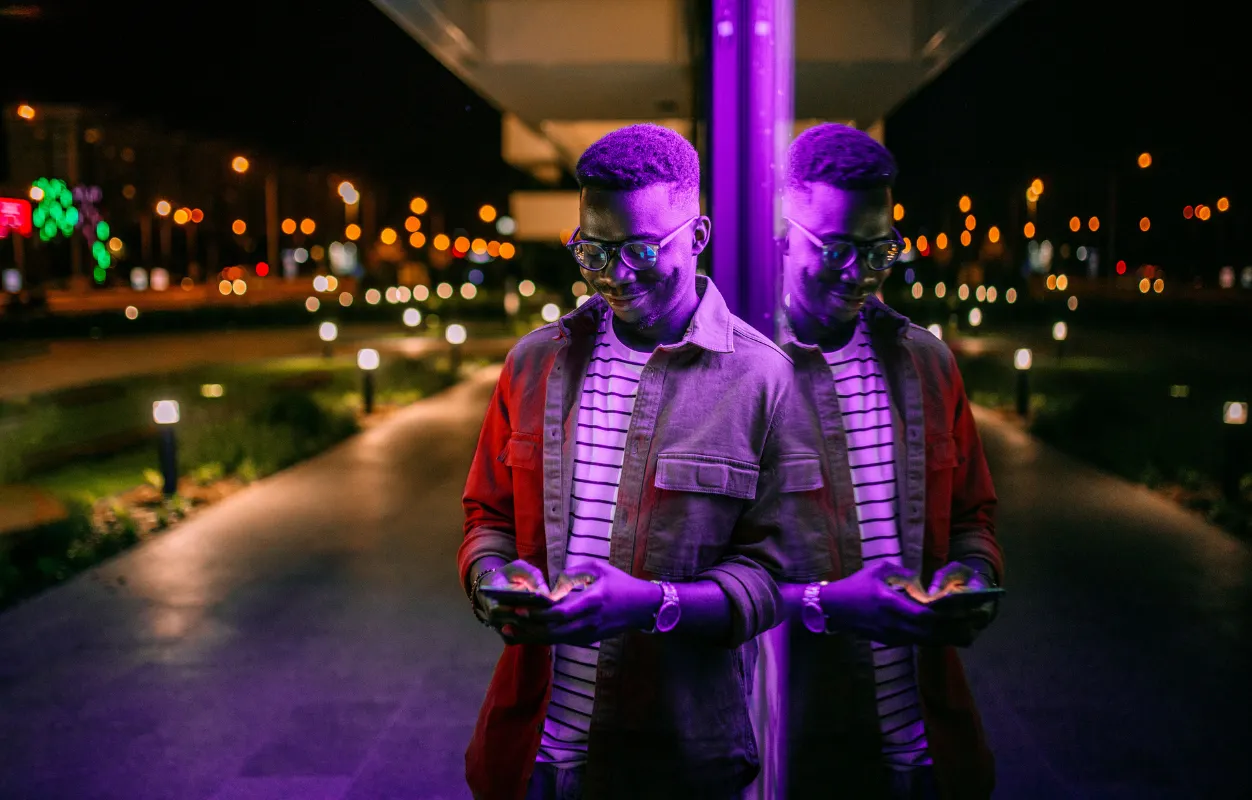 Man standing by a window checking his phone