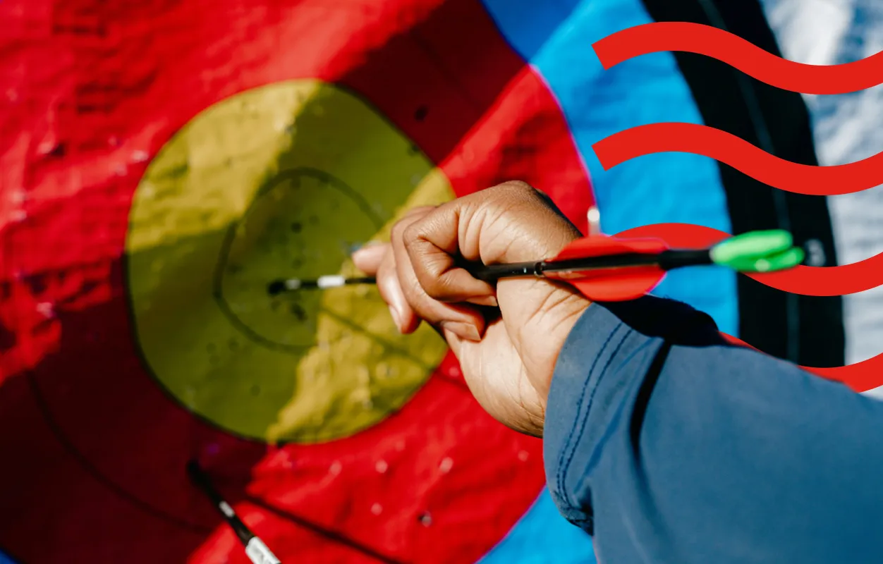 Hand pulling an arrow from the bullseye of an archery target