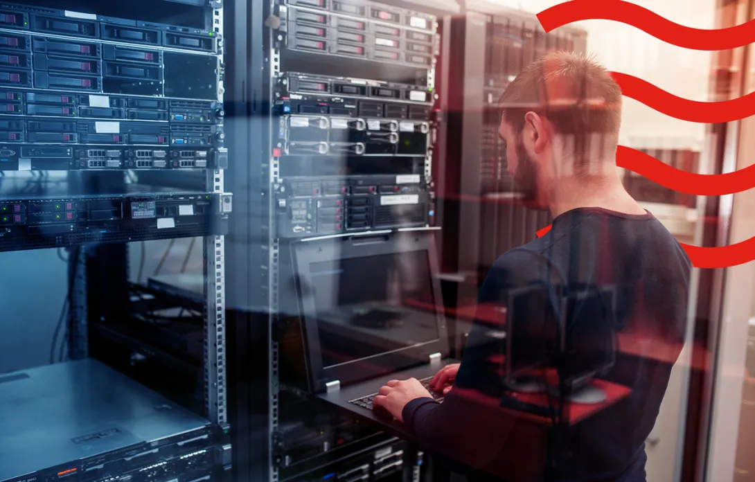 A man typing on his computer in a server room